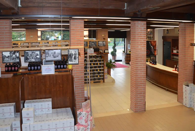 Interni dell'enoteca-cantina Val Tidone: scaffali vini, bottiglie e cassa.