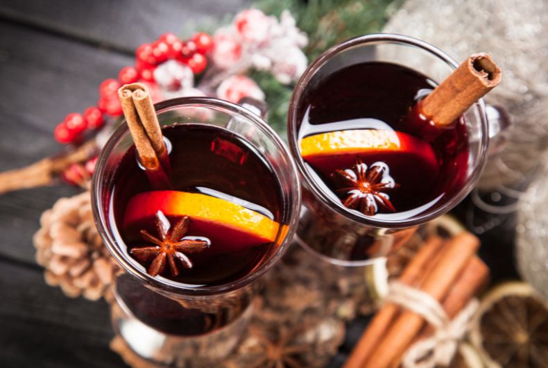 Vin brulé caldo: primi piani di due bicchieri con arancia, cannella e anice stellato. Perfetto per l'inverno e le feste.