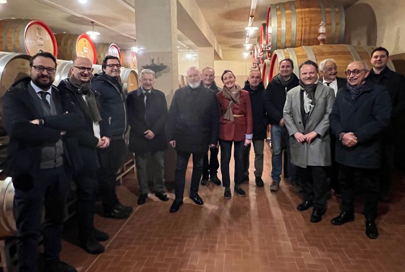 Visita di Stefano Bonaccini alla Cantina Valtidone: gruppo di persone tra le botti di vino, promozione del territorio e prodotti locali piacentini